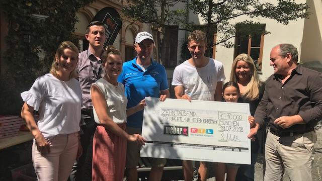 Weber Grill und Thomas Müller: Versteigerung für den guten Zweck Der Scheck über 10.000 Euro wurde von Thomas Müller im Rahmen einer Weber Grillparty übergeben.