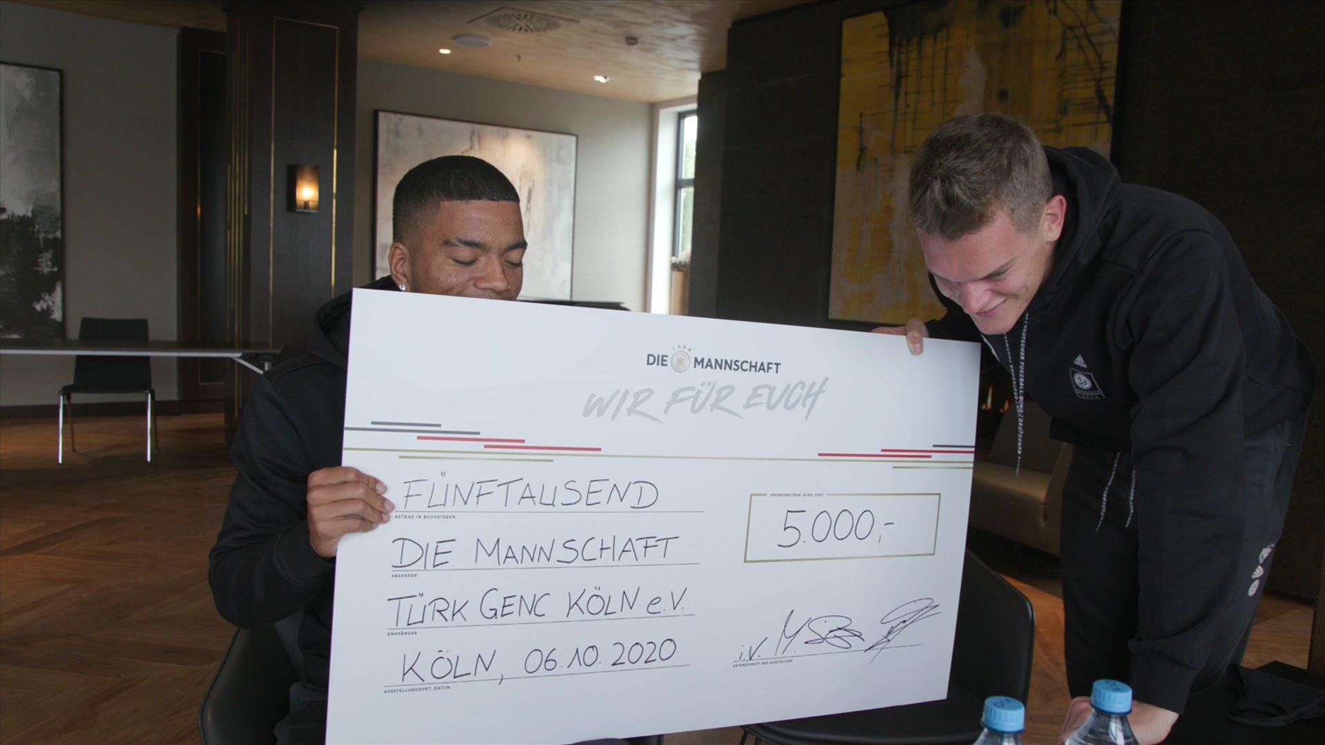 Die Mannschaft macht es möglich: Videochat mit den Fußballhelden und ein neuer Kunstrasenplatz Nationalspieler Matthias Ginter und Benjamin Henrichs überreichen einen Spendenscheck