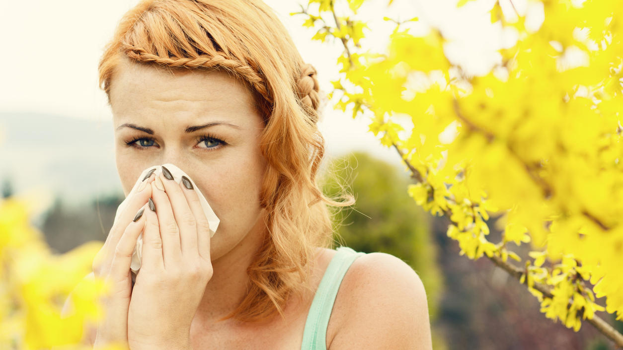 Pollen-Alarm durch Klimawandel: Allergien immer heftiger Young woman sneezing among flowers outdoors