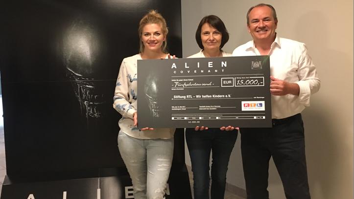 Wolfram Kons gegen Nina Bott: Wer bleibt cooler bei der „Alien-Challenge“? Nina Bott, Eva Conradi und Wolfram Kons mit einem Scheck für „RTL – Wir helfen Kindern“
