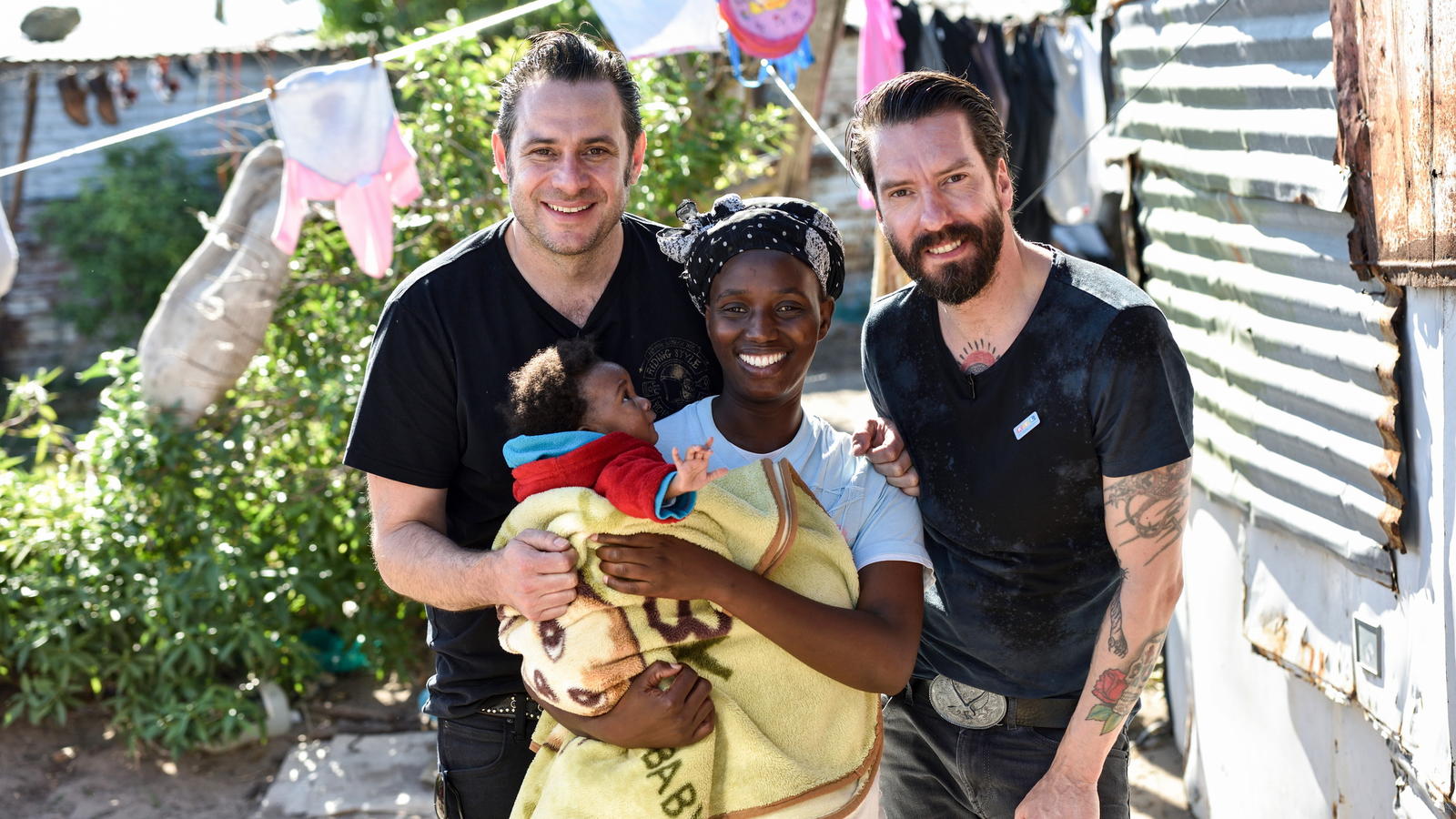 Projektpaten von „RTL – Wir helfen Kindern“: Emotionale Grenzerfahrung für „The BossHoss“ im Township! Alec Völkel (r.) und Sascha Vollmer - The BossHoss - sind Paten der Stiftung "RTL - Wir helfen Kindern". Sie besuchen Tholiswa Mtando (32) mit ihrer Tochter Inganathi (8 Monate) im Township Masakhane in Südafrika.