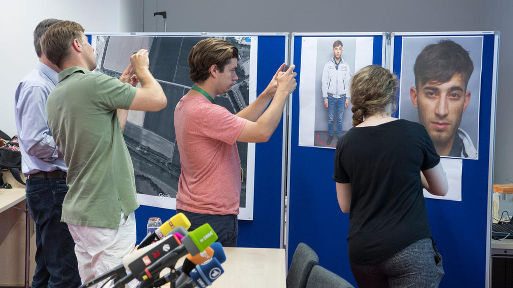 07.06.2018, Hessen, Wiesbaden: Journalisten fotografieren eine Stellwand mit dem polizeilichen Fahndungsfoto des Gesuchten Ali Bashar. Der 20-jährige Iraker gilt im Fall des gewaltsamen Todes von Susanna F. als dringend tatverdächtig und hat sich off