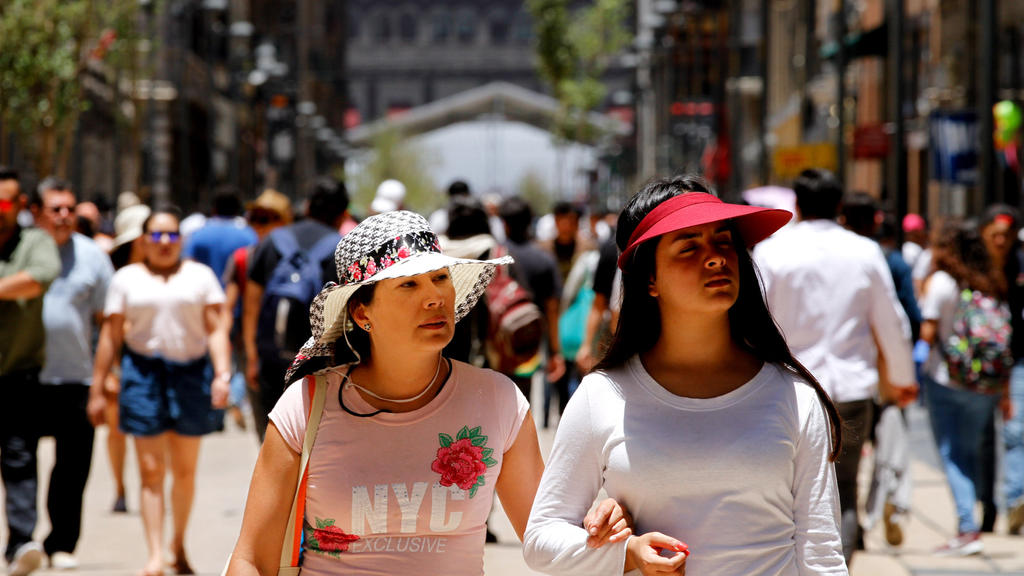 31.05.2018, Mexiko, Mexiko-Stadt: Zwei Frauen spazieren durch den Zentrum der mexikanischen Hauptstadt. Da die Stadt auf 2250 Metern Höhe liegt, ist die Sonne dort besonders intensiv. (zu dpa-Korr "Sombreros, Hydranten, Feuchttücher - weltweite Strat