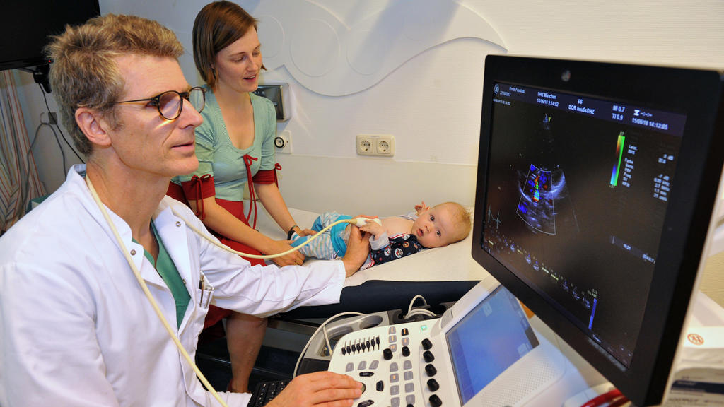 HANDOUT - 15.06.2018, Bayern, München: Peter Ewert, Direktor der Klinik für Angeborene Herzfehler/Kinderkardiologie am Deutschen Herzzentrum München, untersucht das Herz des kleinen Faustus mit Ultraschall, während die Mutter Fanny B. zuschaut. Der k