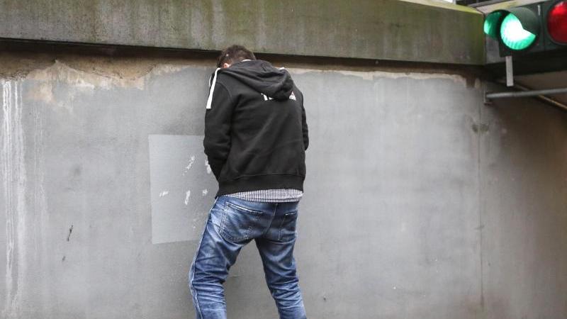 Ein junger Mann steht an einer Wand
