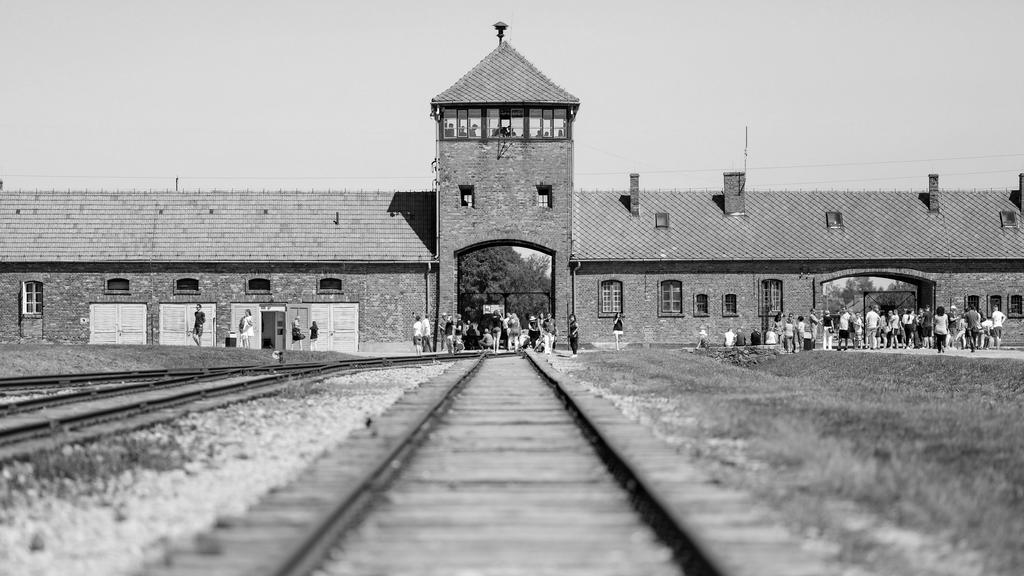 Besucher gehen vor dem historischen Tor (Innenneite) durch das frühere Vernichtungsslager Auschwitz-Birkenau.