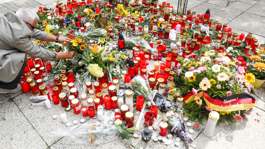 28.08.2018, Sachsen, Chemnitz: Ein Mann legt Blumen am Tatort nieder. Nach einem Streit war in der Nacht zu Sonntag in der Innenstadt von Chemnitz ein 35-jähriger Mann erstochen worden. Die Tat war Anlass für spontane Demonstrationen, bei denen es au