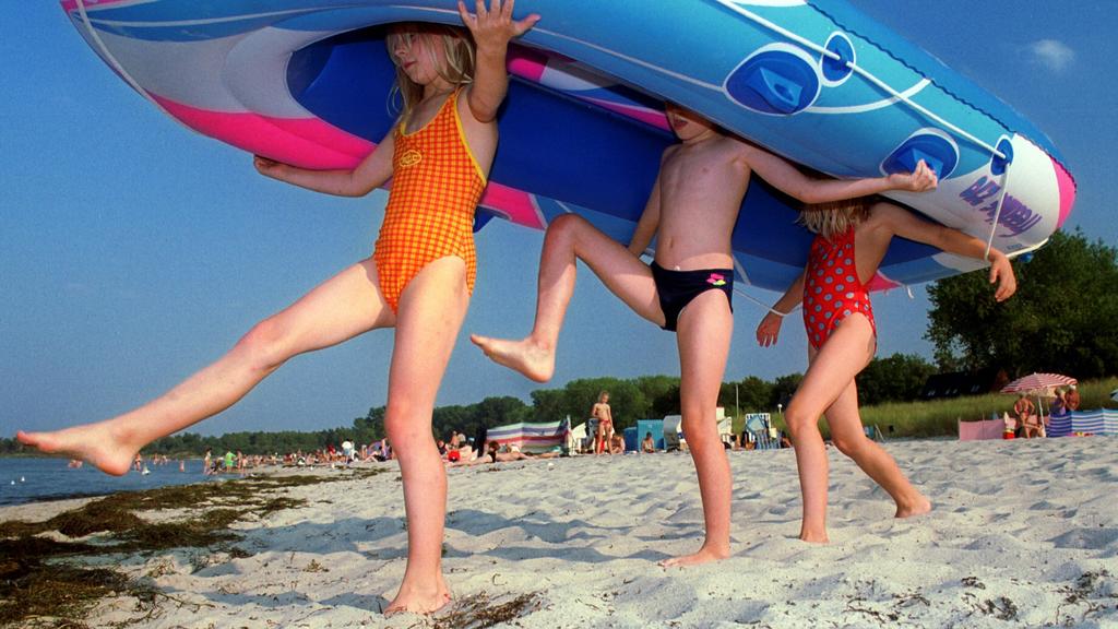 Tarnewitz (Mecklenburg-Vorpommern): Mit ihrem Schlauchboot laufen Kinder am 13.09.1999 am Strand von Tarnewitz (Landkreis Nordwestmecklenburg) Richtung Wasser. Bei hochsommerlichen Temperaturen bis zu 28 Grad und Sonnenschein zieht es Mitte September