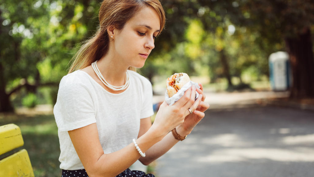 Frau ist Burger alleine im Park.