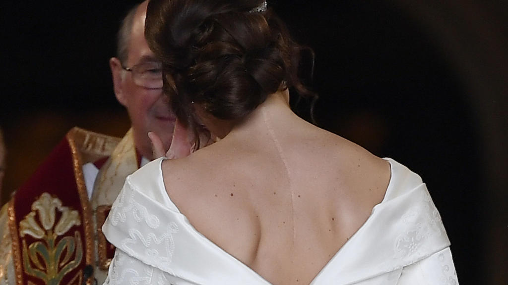 12.10.2018, Großbritannien, Windsor: Die Braut, Prinzessin Eugenie kommt in Begleitung ihres Vaters zu ihrer Hochzeit an der St.-Georges-Kapelle von Schloss Windsor an. Am Rücken ist eine Narbe von einer Skoliose-Operation im Alter von 12 Jahren sich