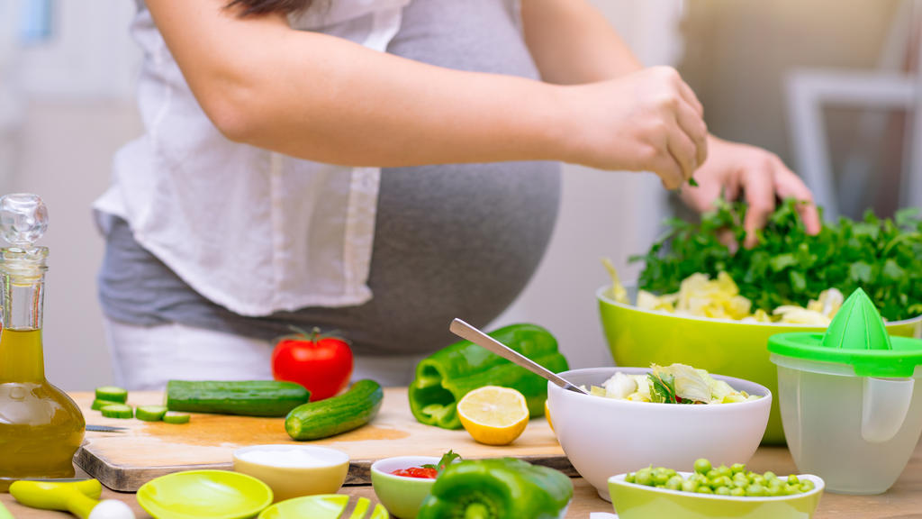Schwangere Frau bereitet gesundes Essen zu