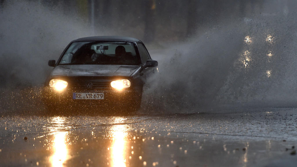 09.03.2019, Nordrhein-Westfalen, Gelsenkirchen: Ein Auto fährt langsam durch eine tiefe Pfütze die sich durch Starkregen auf einer Straße gebildet hat. Mit Sturmböen und Gewitter hat Sturmtief Dragi am Samstagnachmittag in Nordrhein-Westfalen für Pro