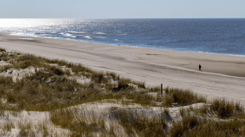 08.04.2019, Schleswig-Holstein, Wenningstedt/Sylt: Ein Mann läuft bei strahlendem Sonnenschein auf der Insel Sylt über einen ansonsten menschenleeren Strand Foto: Axel Heimken/dpa +++ dpa-Bildfunk +++