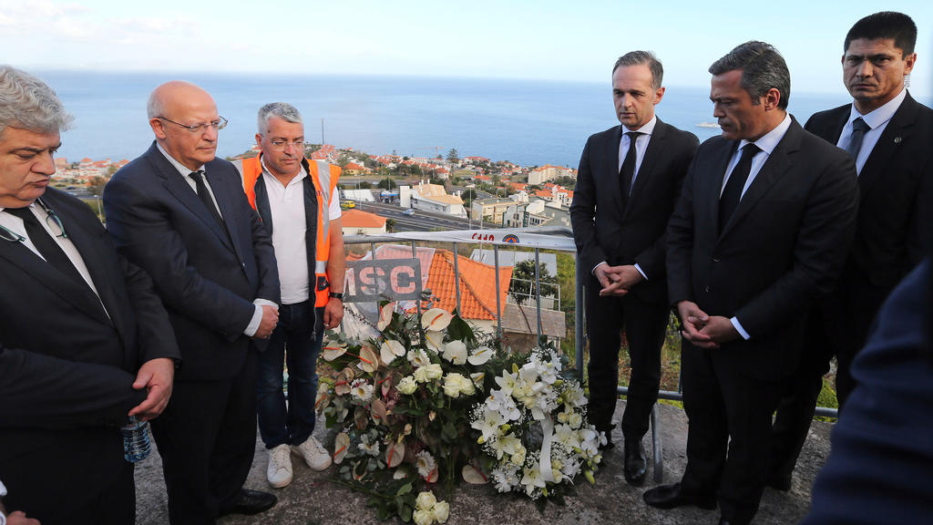 dpatopbilder - 18.04.2019, Portugal, Funchal (Madeira): Heiko Maas (3.v.r), Außenminister von Deutschland, und der portugiesische Außenminister Augusto Santos Silva (2.v.l) stehen an der Unfallstelle eines Busunglücks, nachdem sie einen Kranz gelegt