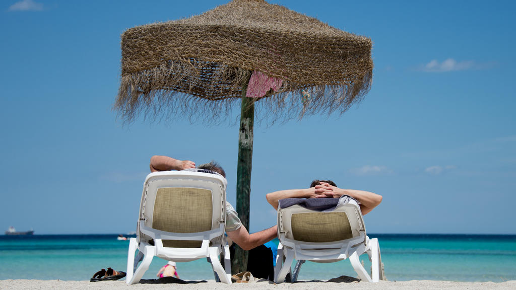 ARCHIV - 09.06.2013, Spanien, Muro: Deutsche Urlauber liegen an einem Strand im Norden der Mittelmeerinsel Mallorca. Millionen Bundesbürger sind so arm, dass sie sich keine Urlaubsreise leisten können. Etwa jeder Siebte konnte im vergangenen Jahr nic