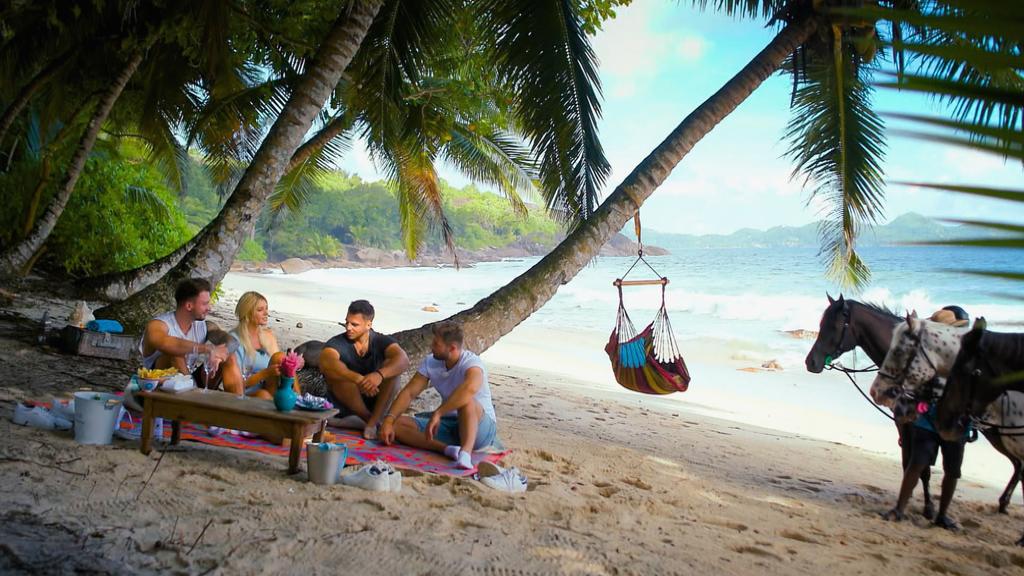 Gerda sitzt mit Keno, Tim und Marco am Strand.