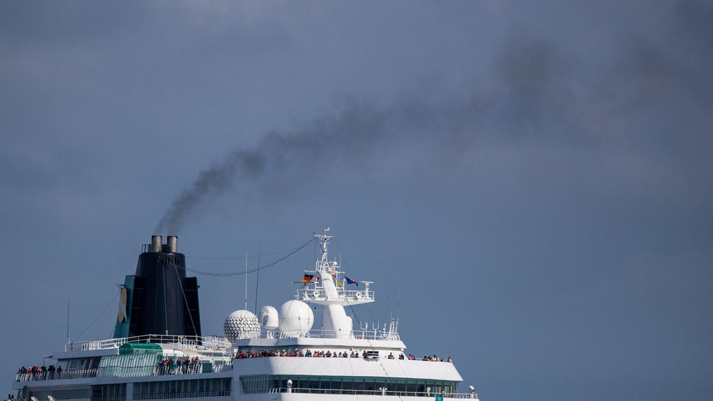 ARCHIV - 09.08.2019, Mecklenburg-Vorpommern, Rostock-Warnemünde: Aus dem Schornstein eines Kreuzfahrtschiffes steigt beim Einlaufen in den Hafen von Rostock eine dunkle Rauchwolke auf. Angesichts einer international boomenden Kreuzfahrtindustrie und