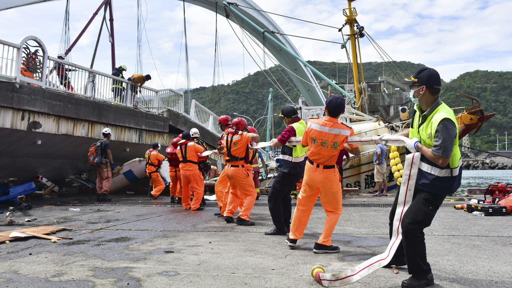 01.10.2019, Taiwan, Nanfangao: Feuerwehrleute und Rettungskräfte arbeiten am Unfallort nach dem Einsturz einer Brücke. Taifun «Mitag» hat in Taiwan eine Brücke einstürzen lassen und auch weitere schwere Schäden hervorgerufen. Nach Angaben der Nationa
