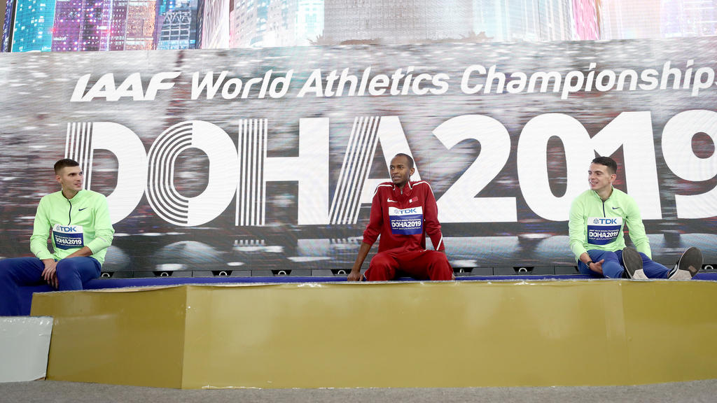 DOHA, QATAR - OCTOBER 04: (L-R) Silver medalist Mikhail Akimenko of Authorised Neutral Athletes, gold medalist Mutaz Essa Barshim of Qatar and bronze medalist Ilya Ivanyuk of Authorised Neutral Athletes wait at the podium as the ceremony for the Men