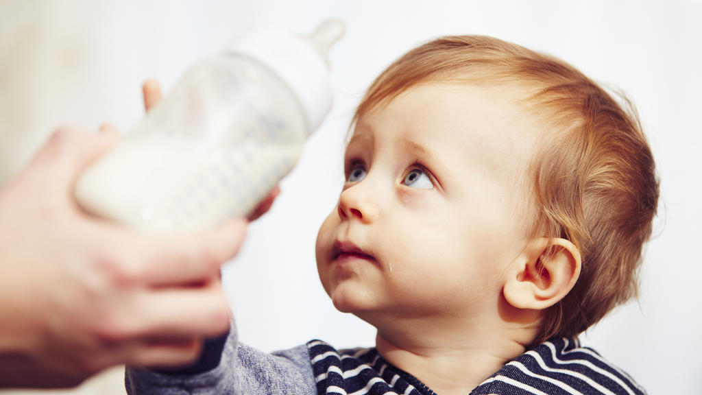 Kleinkind bekommt Flasche mit Milch