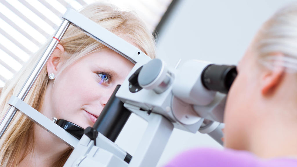 optometry concept - pretty, young female patient having her eyes examined by an eye doctor (color toned image; shallow DOF) | Verwendung weltweit, Keine Weitergabe an Wiederverkäufer.
