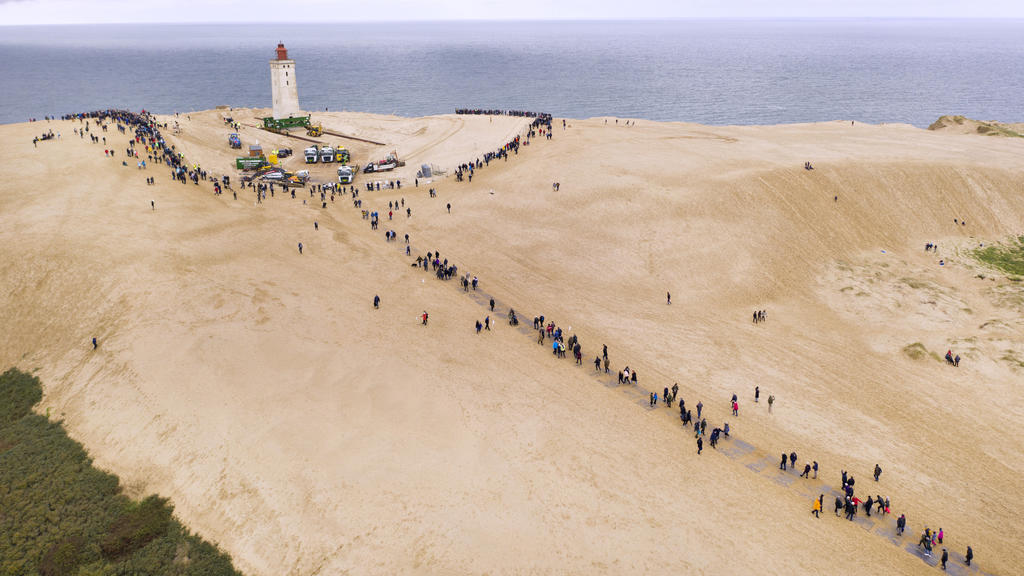 14.09.2017, Dänemark, Loenstrup: Schaulustige wohnen dem "Umzug" eines rund 120 Jahre alten Leuchtturms bei. Der Leuchtturm Rubjerg Knude Fyr war 1899 auf einer Wanderdüne errichtet worden. Aufgrund der Erosion der Küste drohte er ins Meer zu stürzen