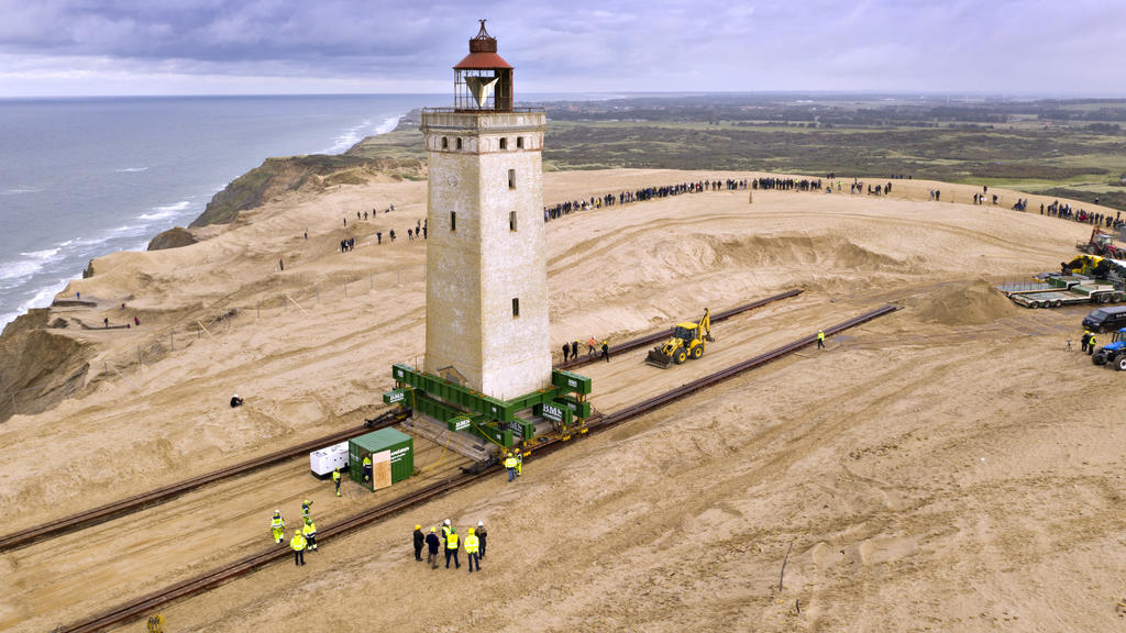 14.09.2017, Dänemark, Loenstrup: Schaulustige wohnen dem "Umzug" eines rund 120 Jahre alten Leuchtturms bei. Der Leuchtturm Rubjerg Knude Fyr war 1899 auf einer Wanderdüne errichtet worden. Aufgrund der Erosion der Küste drohte er ins Meer zu stürzen