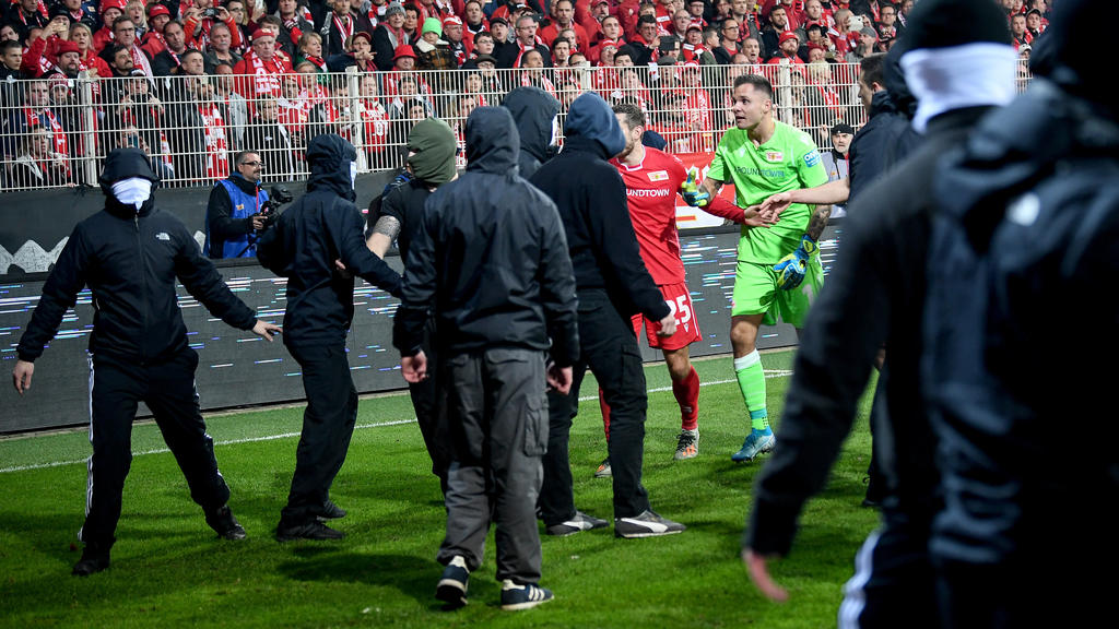 02.11.2019, Berlin: Fußball: Bundesliga, 10. Spieltag: 1. FC Union Berlin - Hertha BSC in der Alten Försterei. Unions Christopher Lenz und Unions Rafal Gikiewicz beruhigen vermuimmte Fans ihres Vereins nachdem die Hertha-Fans Pyrotechnik auf das Spie