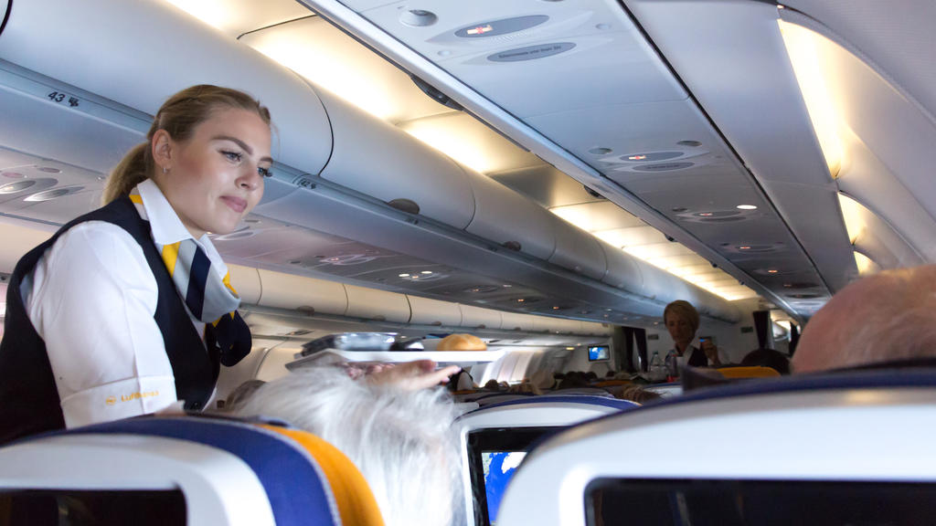 Munich: A female flight attendant is serving the lunch to a passenger sitting in the economy class of the route Munich - Vancouver of Lufthansa Airlines.