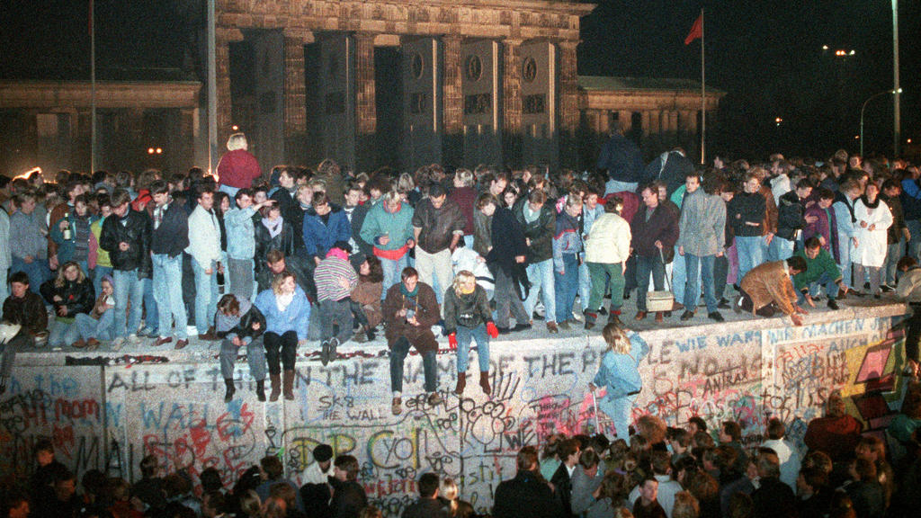 Menschen auf der Berliner Mauer vor dem Brandenburger Tor in der Nacht vom 9. auf den 10.11.1989. Vom 13.08.1961, dem Tag des Mauerbaus, bis zum Mauerfall am 09.11.1989 waren die Bundesrepublik Deutschland und die DDR durch den "Eisernen Vorhang" zwi