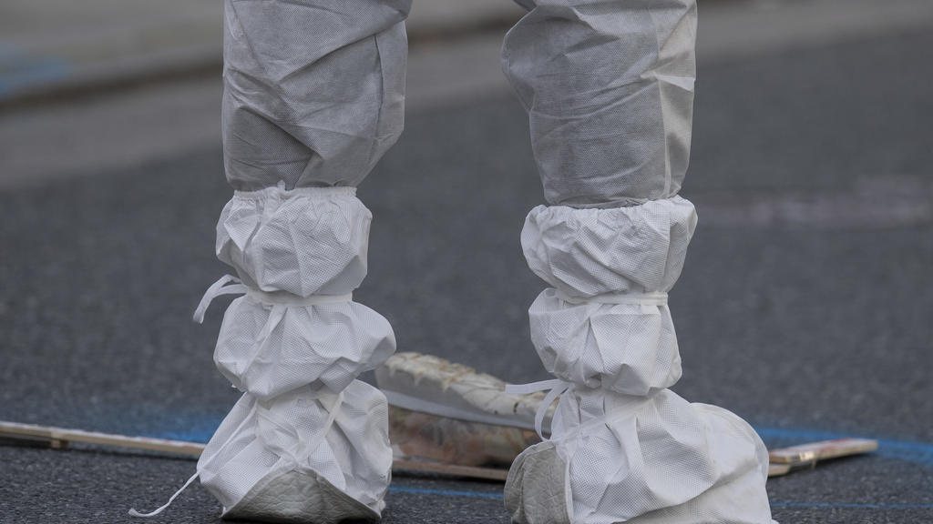 25.10.2019, Hessen, Limburg An Der Lahn: Eine Mitarbeiterin der Spurensicherung dokumentiert einen Schuh, der nach der Tötung einer Frau in der Innenstadt auf der Straße liegt. Nach bisherigen Ermittlungen der Polizei hatte ein 34-jähriger Mann seine
