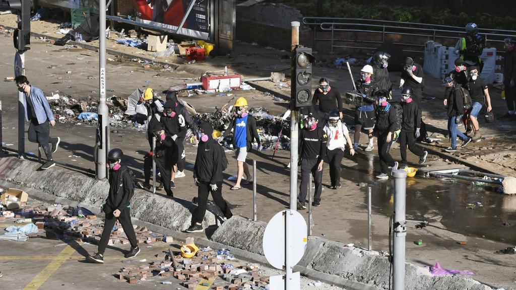19.11.2019, China, Hongkong: Junge Demonstranten verlassen die Hong Kong Polytechnic University im Bezirk Kowloon nach Zusammenstößen mit der Polizei an der Universität, in der sie sich verbarrikadiert haben. Anfang Dienstag erlaubte die Polizei den