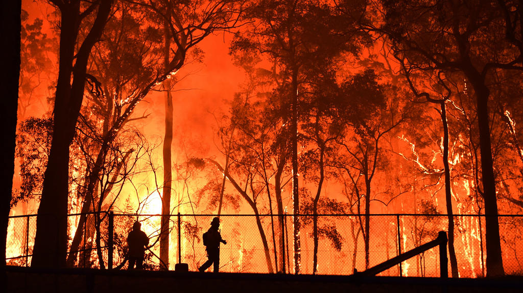 dpatopbilder - 19.11.2019, Australien, Colo Heights: Zwei Feuerwehrleute sind im Einsatz, um die Colo Heights Public School zu schützen. Wegen der Buschbrände in der Umgebung von Sydney wird die Lage auch in Australiens Millionenmetropole selbst zune