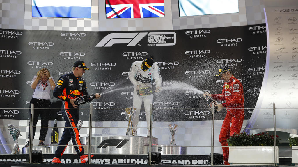 2019 Abu Dhabi GP YAS MARINA CIRCUIT, UNITED ARAB EMIRATES - DECEMBER 01: Max Verstappen, Red Bull Racing, 2nd position, Lewis Hamilton, Mercedes AMG F1, 1st position, and Charles Leclerc, Ferrari, 3rd position, celebrate on the podium with Champagne