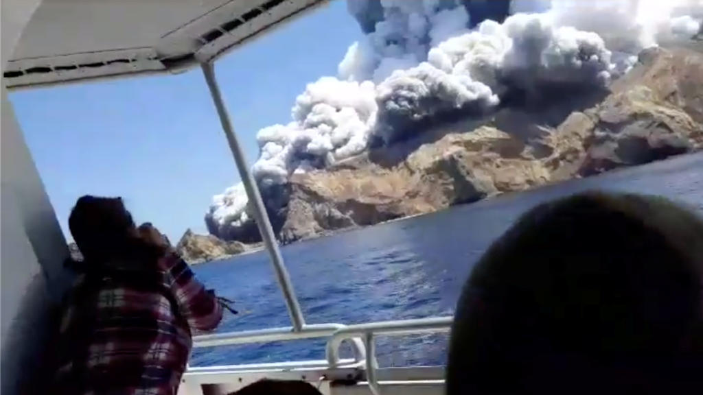 People on a boat react as smoke billows from the volcanic eruption of Whakaari, also known as White Island, New Zealand December 9, 2019 in this picture grab obtained from a social media video. INSTAGRAM @ALLESSANDROKAUFFMANN/via REUTERS THIS IMAGE H