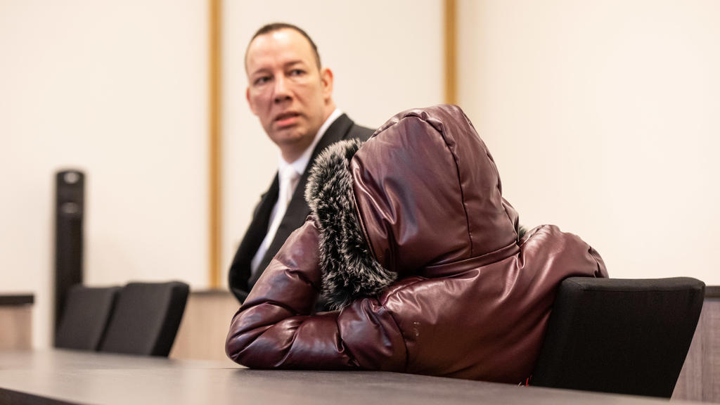 07.01.2020, Nordrhein-Westfalen, Duisburg: Einer der bei der Vergewaltigung einer jungen Frau mutmaßlich beteiligten Jugendlichen (r) sitzt mit einer Kapuze über dem Kopf im Gerichtssaal neben Marc Decker, seinem Anwalt. Fünf Jugendliche sollen in Mü