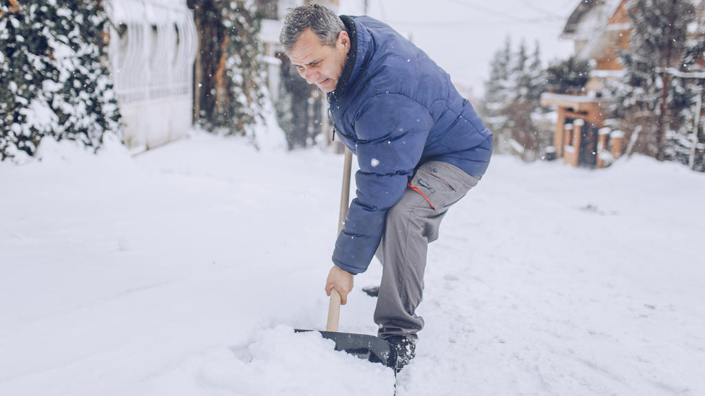 Alter Mann beim Schnee schippen