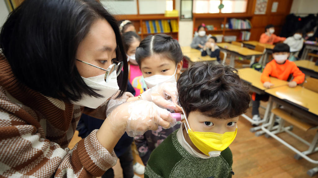 30.01.2020, Südkorea, Seoul: Eine Lehrerin misst am ersten Schultag nach den Winterferien die Temperaturen eines Grundschülers. Die Zahl der Infektionen und Todesopfer durch die Lungenkrankheit aus China ist erneut gestiegen. Foto: -/YNA/dpa +++ dpa-