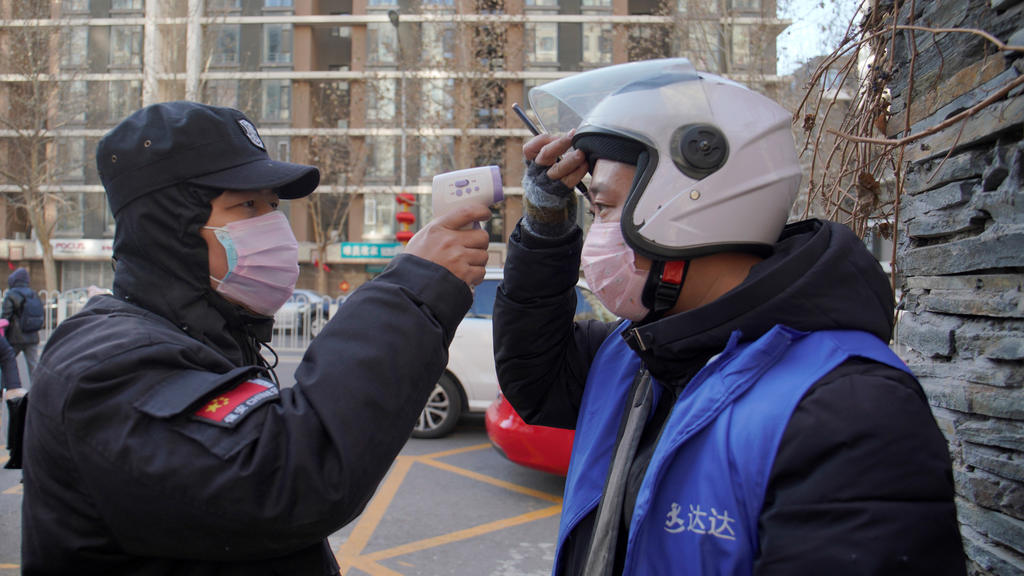 A security officer takes body temperature measurement of a delivery worker at a residential compound in Beijing, China as the country is hit by an outbreak of the new coronavirus, February 1, 2020. REUTERS/Stringer NO RESALES. NO ARCHIVES.