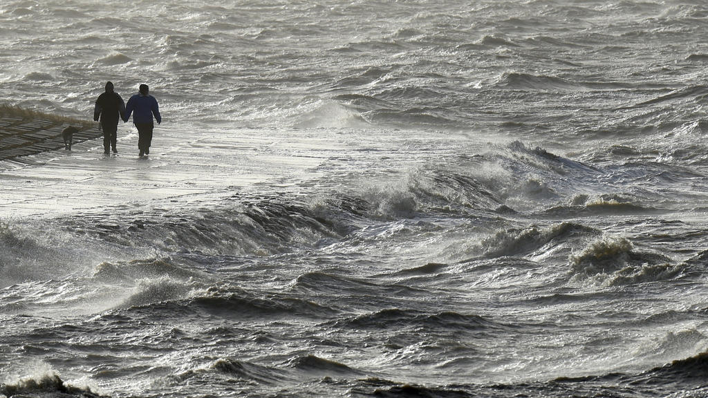 ARCHIV - 09.01.2015, Schleswig-Holstein, Dagebüll: Passanten trotzen am Nordseedeich dem Sturm. (zu dpa "Meteorologen warnen vor heftigen Sturmtief am Wochenende") Foto: Carsten Rehder/dpa +++ dpa-Bildfunk +++