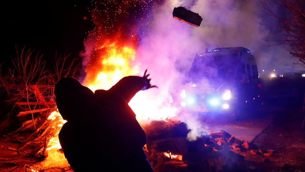 A demonstrator throws a stone towards a police van during a protest against the arrival of a plane carrying evacuees from coronavirus-hit China's Hubei province in the village of Novi Sanzhary in Poltava region, Ukraine February 20, 2020. Local resid