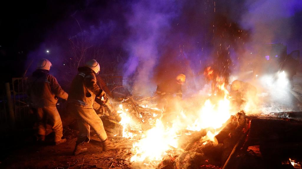 Ukrainian firefighters clear the way as demonstrators block a road during a protest against the arrival of a plane carrying evacuees from coronavirus-hit China's Hubei province in the village of Novi Sanzhary in Poltava region, Ukraine February 20, 2