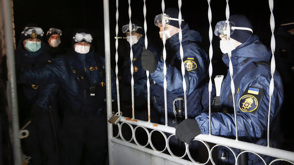 National Guard soldiers close the gate of the sanitarium where Ukrainian passengers evacuated from the Chinese city of Wuhan will stay for two weeks, outside Novi Sarzhany, Ukraine, Thursday, Feb. 20, 2020. Since the early morning, several hundred re