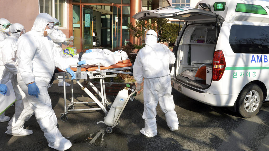 Medial workers wearing protective gears carry a patient suspected of contracting the new coronavirus toward an ambulance at Daenam Hospital in Cheongdo, South Korea, Friday, Feb. 21, 2020. South Korea reported 100 new virus cases Friday, bringing the