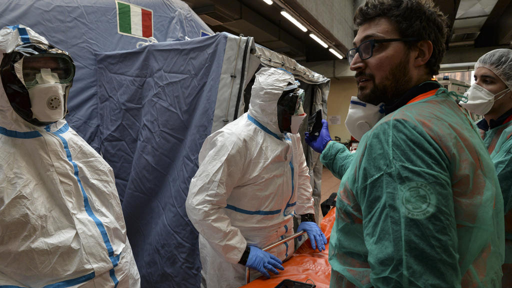 25.02.2020, Italien, Turin: Mitarbeiter in Schutzanzügen stehen in einem Krankenhaus neben einer Liege. Bei dem neuen Coronavirus steigt in Italien die Zahl der Toten und Infizierten weiter an. Foto: Diego Puletto/SOPA Images via ZUMA Wire/dpa +++ dp