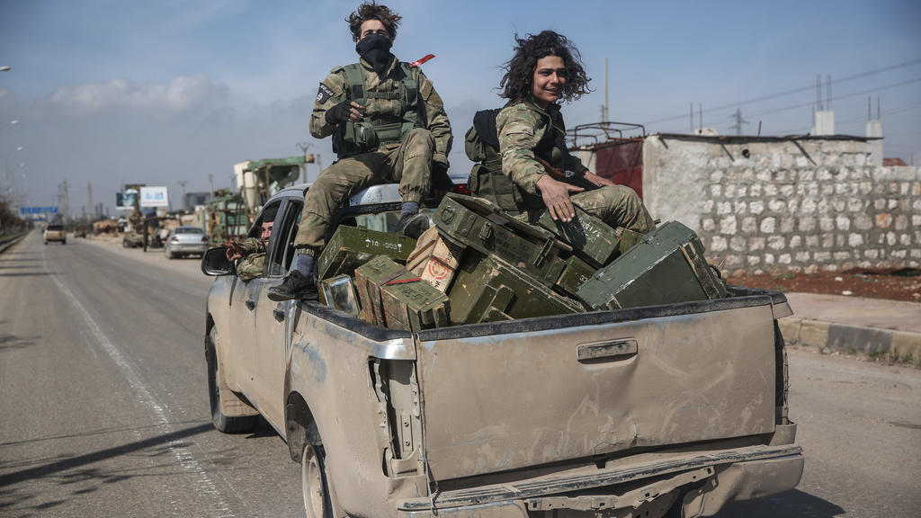 27.02.2020, Syrien, Sarakib: Kämpfer der Nationalen Befreiungsfront (NFL) patrouillieren auf einer Straße. Oppositionelle Milizen sollen mit türkischer Unterstützung den strategisch wichtigen Ort im Kampf um Syriens letzte große Rebellenhochburg um d