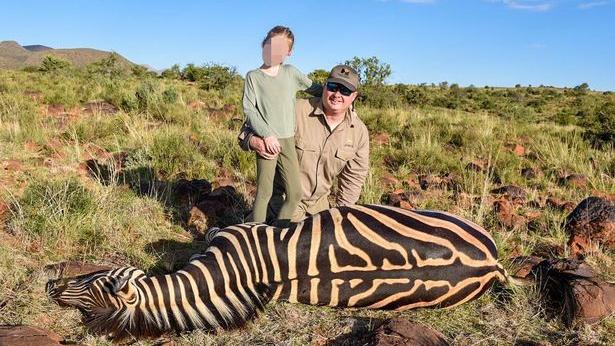 Ein neunjähriges Mädchen posiert neben einem toten Zebra.