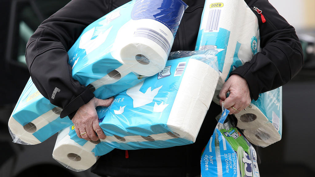 ARCHIV - 18.03.2020, Nordrhein-Westfalen, Siegen: Ein Mann trägt eingekauftes Toilettenpapier und Küchenrollen aus einem Supermarkt. Auch wenn das neuartige Coronavirus beängstigend ist, haben viele Menschen ihren Humor noch nicht verloren. So leer,