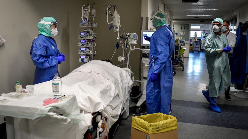 19.03.2020, Italien, Brescia: Medizinisches Personal behandeln am Gang der Intensivstation des Krankenhauses von Brescia einen Patienten. In der Lombardei liegen die Metropole Mailand und die heftig von der Krankheit Covid-19 betroffene Zone um Berga