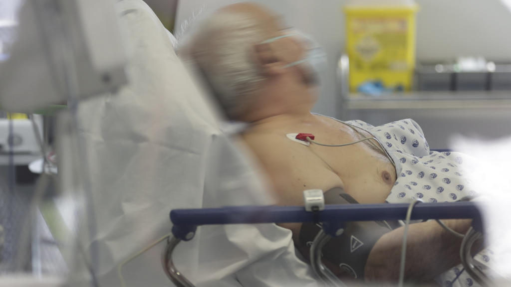 25.03.2020, Belgien, Lüttich: Ein Covid-19-Patient mit Mundschutz liegt auf einem Bett in der Intensivstation des CHU-Krankenhauses. Foto: Pool Olivier Hoslet/BELGA/dpa +++ dpa-Bildfunk +++